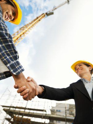 female architect and construction worker shaking hands. Low angle view, copy space